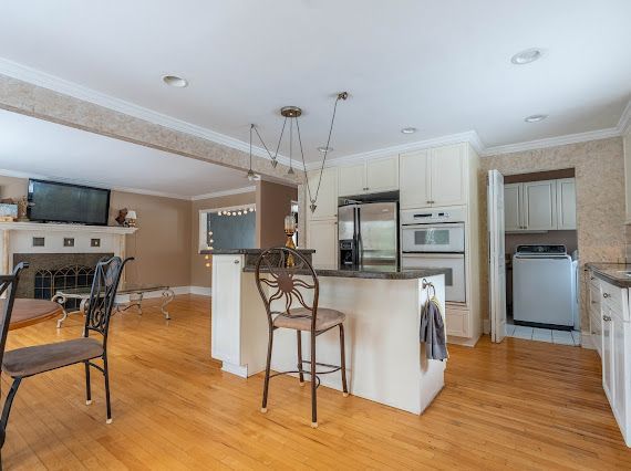 kitchen featuring double oven, light wood-style flooring, a fireplace, stainless steel fridge with ice dispenser, and washer / dryer