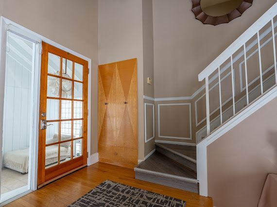 entryway featuring a high ceiling, stairway, wood finished floors, and a decorative wall