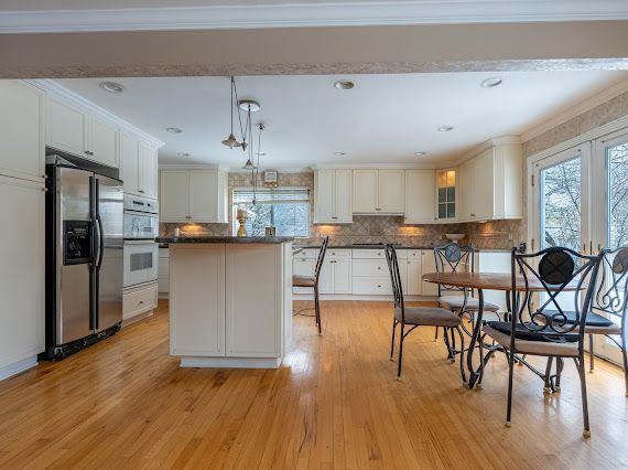 kitchen with light wood finished floors, decorative backsplash, dark countertops, ornamental molding, and stainless steel refrigerator with ice dispenser