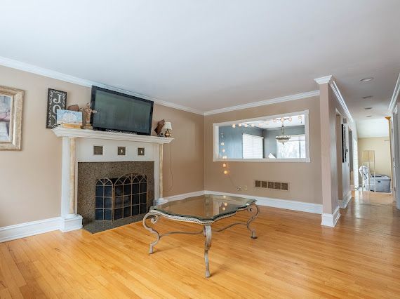 living area with ornamental molding, visible vents, baseboards, and wood finished floors