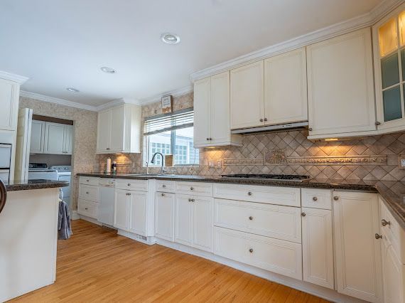 kitchen featuring a sink, washer and dryer, light wood finished floors, glass insert cabinets, and crown molding