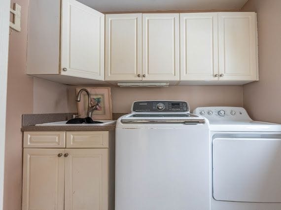 laundry area featuring cabinet space, a sink, and washer and clothes dryer