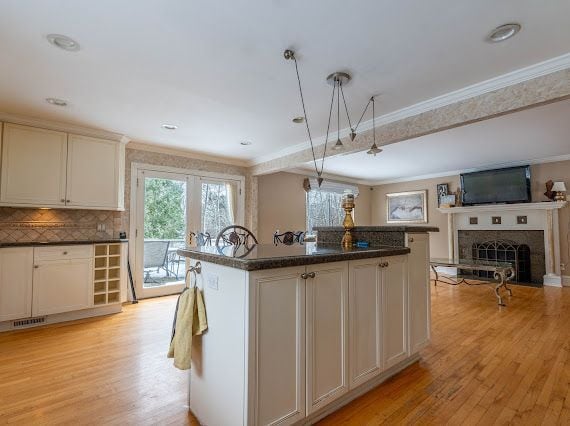 kitchen featuring light wood-style floors, dark countertops, a fireplace, and ornamental molding