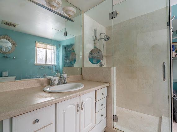 full bathroom with a stall shower, visible vents, and vanity