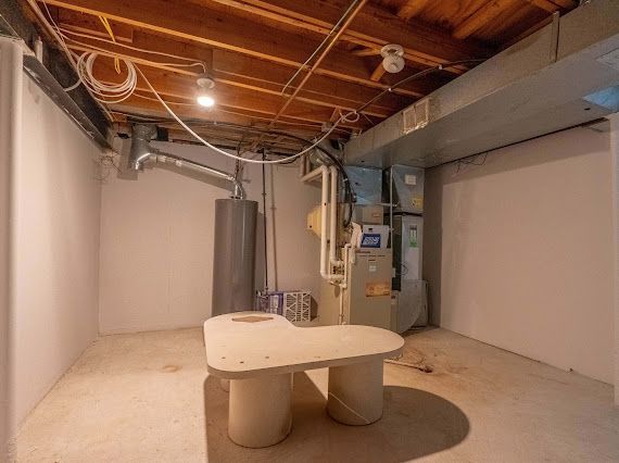 unfinished below grade area featuring gas water heater and heating unit