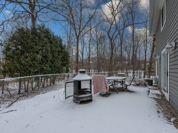 yard covered in snow featuring outdoor dining space and fence