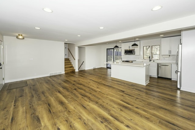 kitchen featuring decorative light fixtures, appliances with stainless steel finishes, dark hardwood / wood-style flooring, a kitchen island, and white cabinets