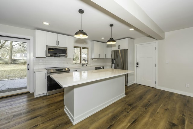 kitchen with white cabinetry, stainless steel appliances, decorative backsplash, a kitchen island, and decorative light fixtures