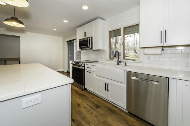 kitchen with appliances with stainless steel finishes, pendant lighting, sink, white cabinets, and dark wood-type flooring