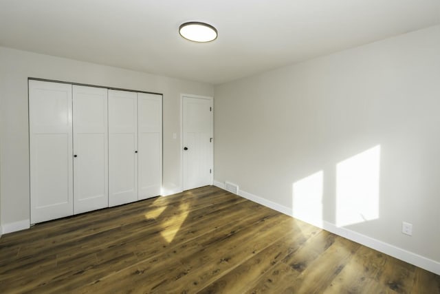 unfurnished bedroom featuring dark hardwood / wood-style floors and a closet