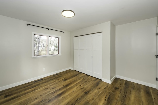 unfurnished bedroom featuring dark hardwood / wood-style flooring and a closet