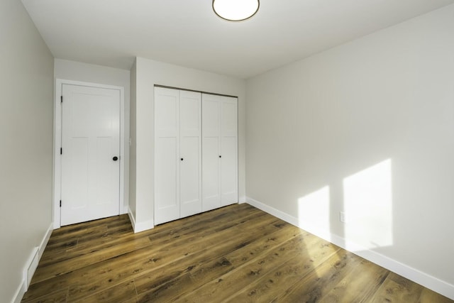 unfurnished bedroom with dark hardwood / wood-style flooring and a closet