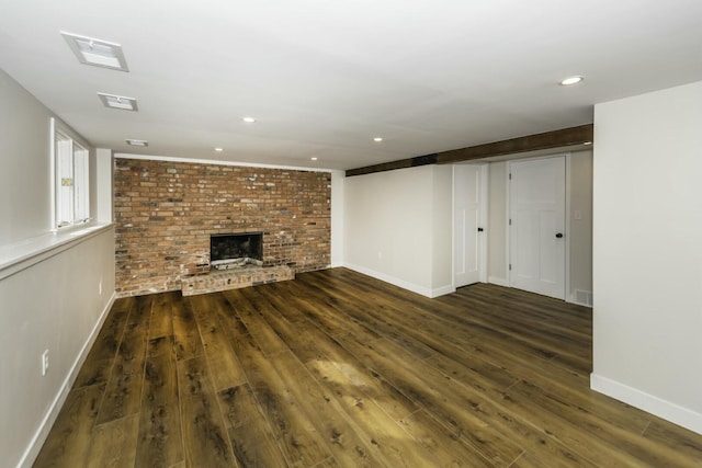 unfurnished living room with brick wall, a brick fireplace, and dark hardwood / wood-style floors