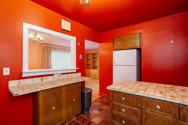 kitchen with tile counters, a chandelier, and white fridge