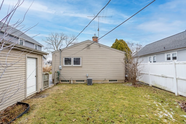 rear view of house with central AC and a yard