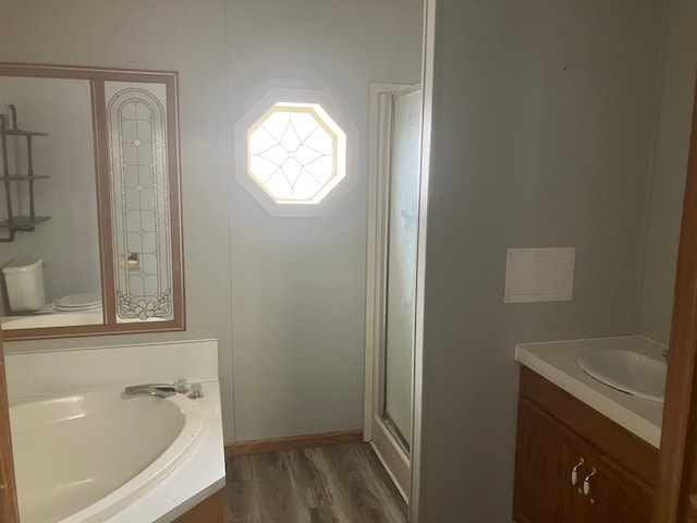 full bathroom featuring toilet, a shower with shower door, vanity, wood finished floors, and a bath