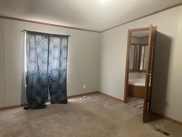 unfurnished room with a textured ceiling, visible vents, baseboards, carpet, and crown molding