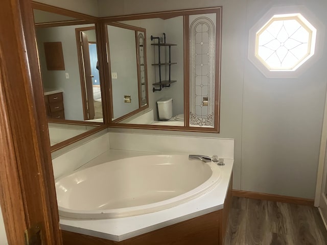 bathroom with vanity, a tub to relax in, wood-type flooring, and toilet