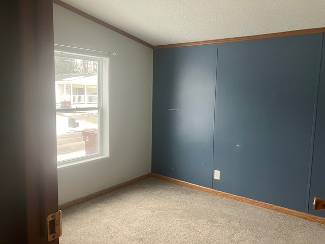 unfurnished room featuring a textured ceiling, baseboards, vaulted ceiling, and carpet flooring