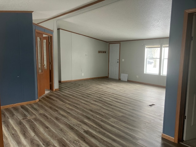 unfurnished room with a textured ceiling, visible vents, vaulted ceiling, and dark wood-type flooring