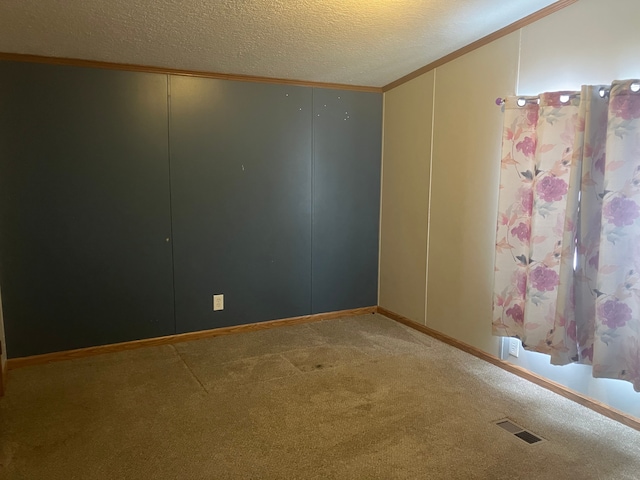 carpeted spare room featuring lofted ceiling, visible vents, crown molding, and a textured ceiling