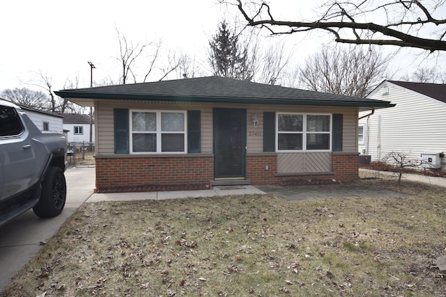 bungalow with brick siding and a front lawn