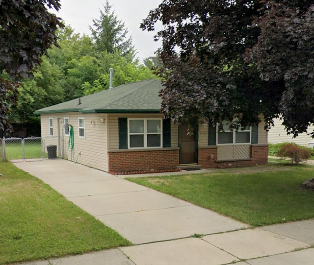 view of front of home with brick siding, a front lawn, and a gate