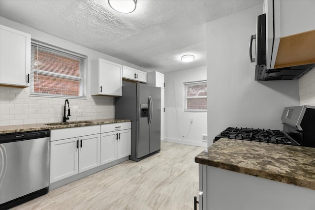 kitchen with sink, dark stone countertops, white cabinetry, and stainless steel appliances