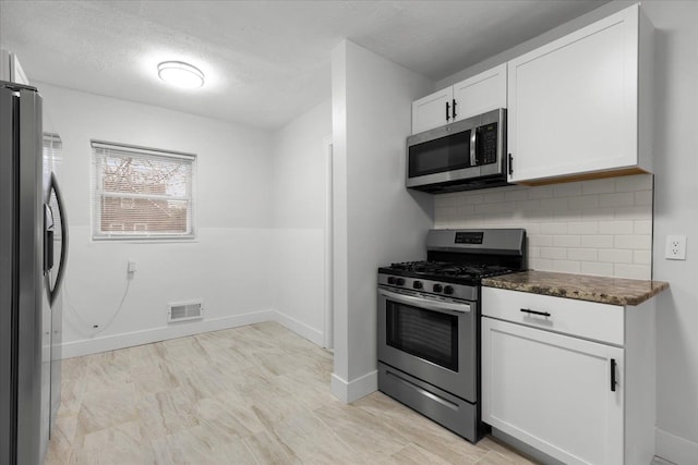 kitchen featuring a textured ceiling, white cabinets, stainless steel appliances, and decorative backsplash