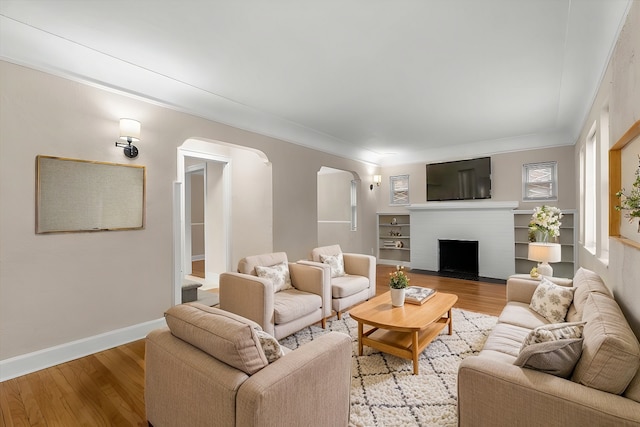 living room with ornamental molding, a brick fireplace, and light hardwood / wood-style floors