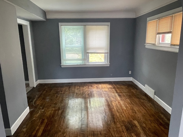 empty room with a healthy amount of sunlight and dark hardwood / wood-style flooring