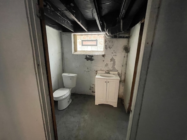 bathroom with concrete flooring, vanity, and toilet