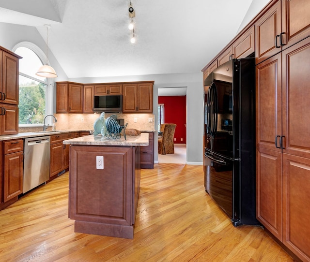 kitchen featuring lofted ceiling, a center island, black fridge, decorative backsplash, and stainless steel dishwasher