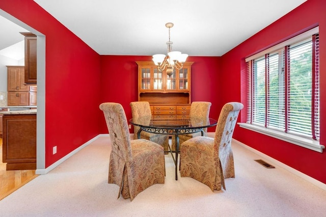 carpeted dining area featuring a chandelier