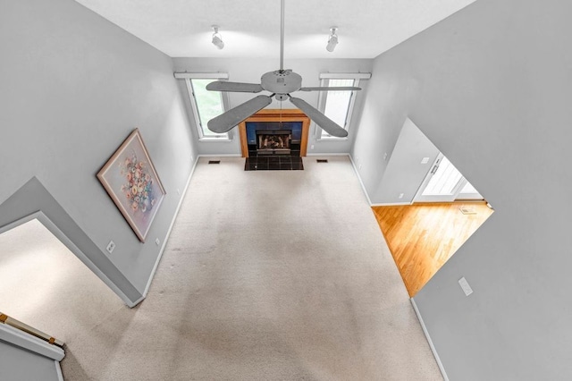 carpeted living room with a tiled fireplace and ceiling fan