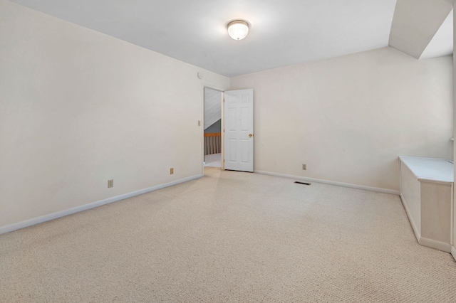 carpeted spare room featuring vaulted ceiling