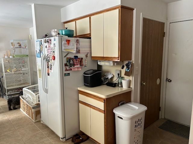 kitchen featuring light tile patterned floors, white refrigerator with ice dispenser, and light countertops