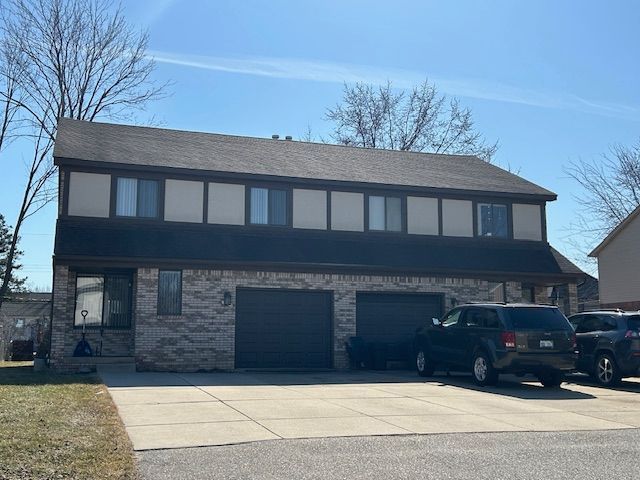 view of front facade featuring concrete driveway, a garage, and brick siding