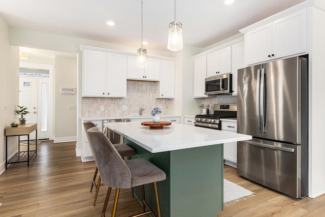 kitchen featuring tasteful backsplash, stainless steel appliances, white cabinets, and a kitchen island