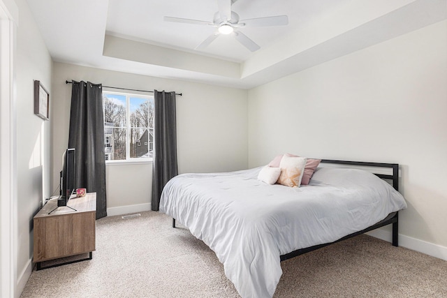 carpeted bedroom featuring a tray ceiling and ceiling fan