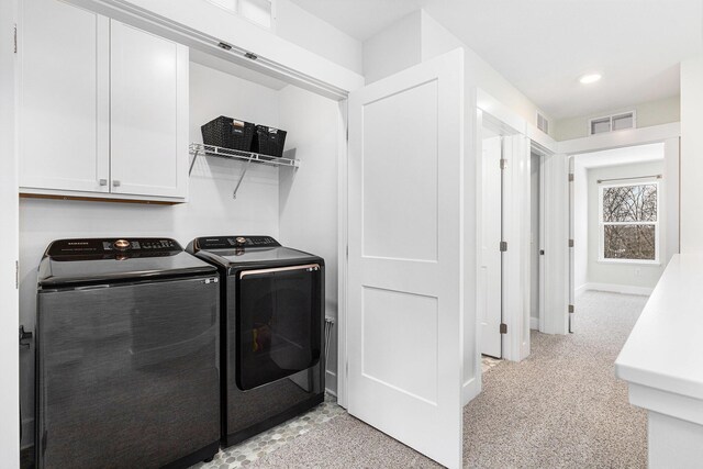 laundry area featuring cabinets, washer and clothes dryer, and light carpet