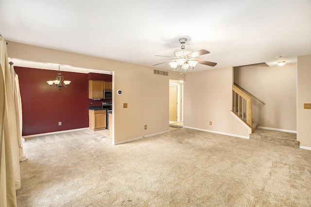 unfurnished living room featuring ceiling fan with notable chandelier and light colored carpet