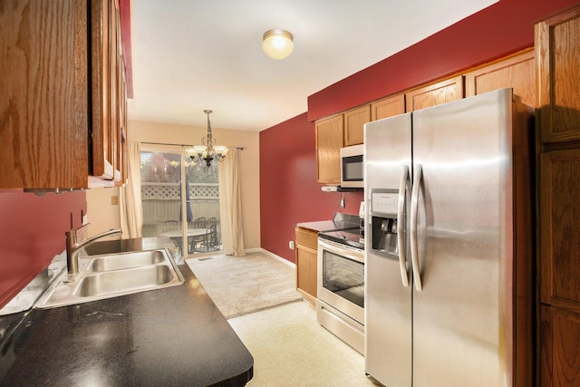 kitchen featuring stainless steel appliances, sink, pendant lighting, and an inviting chandelier