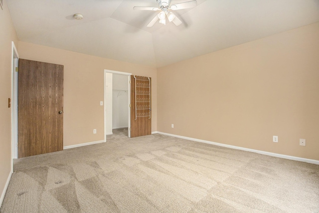 unfurnished bedroom featuring lofted ceiling, a spacious closet, light colored carpet, ceiling fan, and a closet