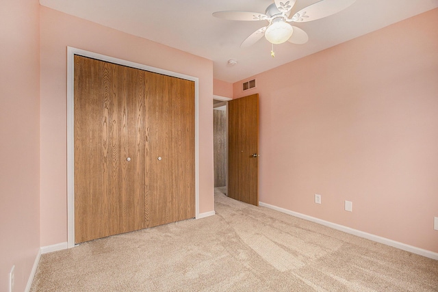 unfurnished bedroom featuring light colored carpet, ceiling fan, and a closet