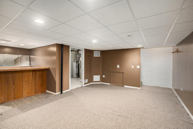 basement with water heater, light carpet, and a drop ceiling