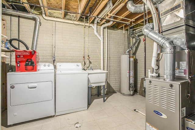 laundry room with washing machine and clothes dryer, sink, heating unit, brick wall, and water heater