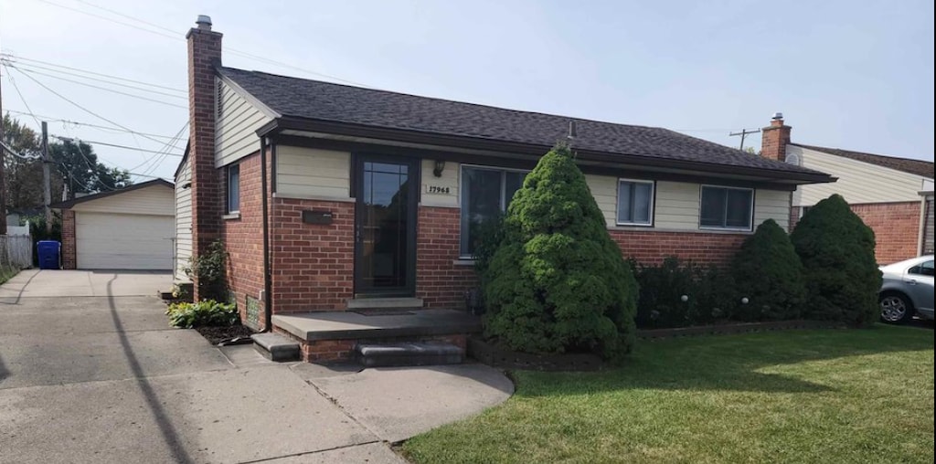 single story home featuring a garage, an outdoor structure, and a front lawn