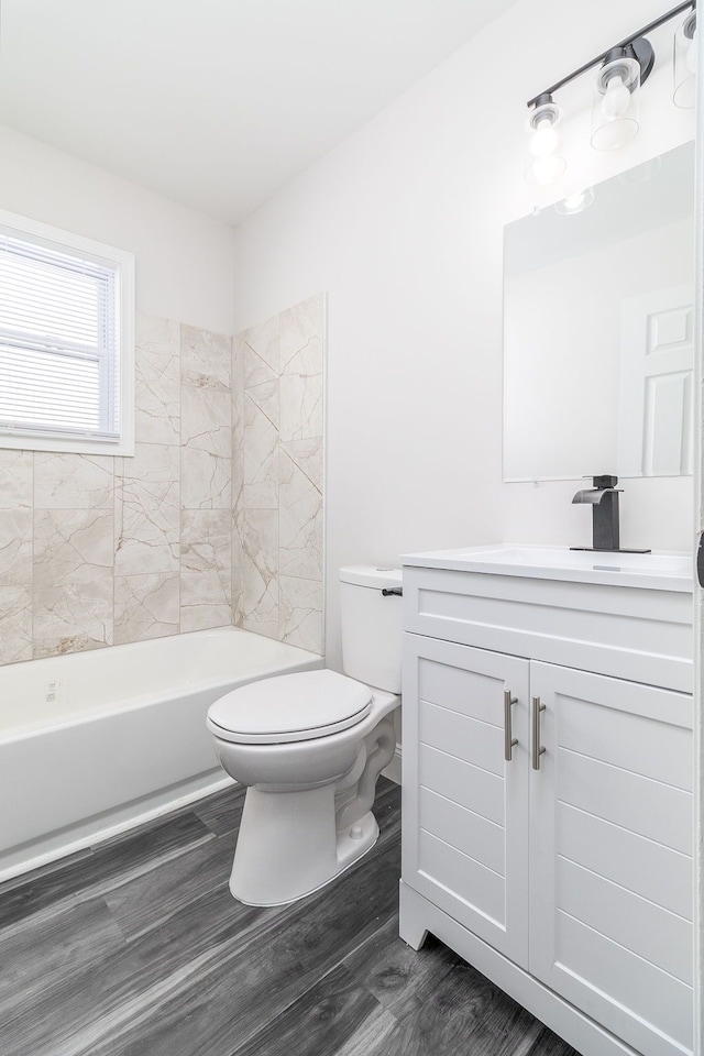 full bathroom featuring toilet, vanity, tiled shower / bath combo, and wood-type flooring