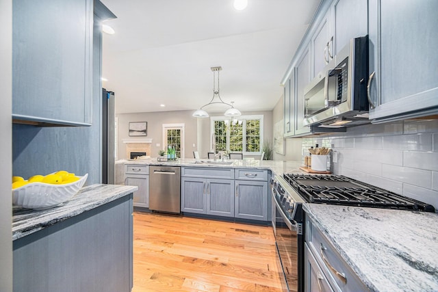 1115 Nature Trl, Manchester, MI 48158 - kitchen featuring sink, appliances with stainless steel finishes, backsplash, decorative light fixtures, and light wood-type flooring